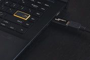 Black USB Data Blocker Pro (USB-A) connected to laptop USB port – secure charge-only setup